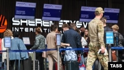 Пассажиры у стоек регистрации в международном аэропорту Шереметьево. Россия, Московская область, 2023 год