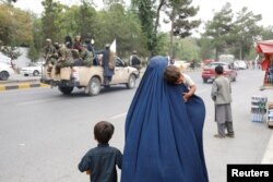 Ооганстандык аял балдарын көтөрүп баратат. Сүрөт иллюстрация үчүн колдонулду.