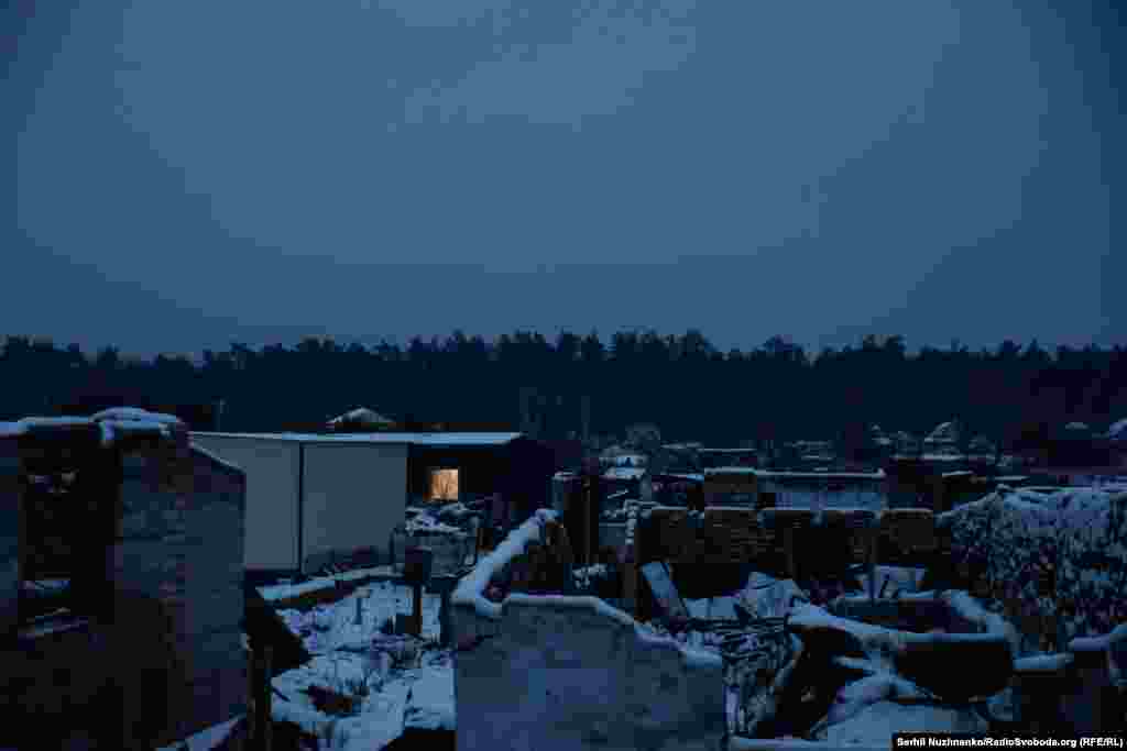 Мощун накривають вечірні сутінки. Серед руїн де-не-де, у маленьких вікнах модульних будинків загоряється світло&nbsp;