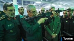 محمد باقری رئیس ستاد کل نیروهای مسلح (نفر وسط) در یک نمایشگاه نظامی اسلحه به دست گرفته است