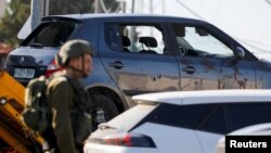 Ичиндеги үч палестиналык өлтүрүлгөн машиненин жанында турган израил аскери. 25-июль, 2023-жыл. 