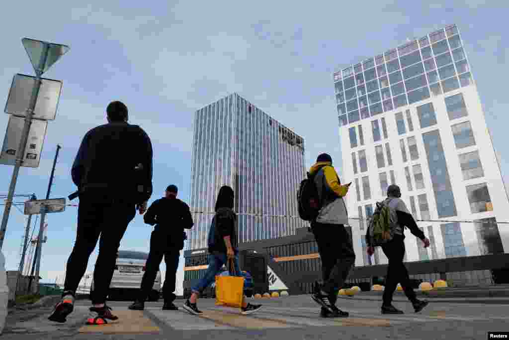 People cross a road next to the site of the damaged building in Moscow. &nbsp;