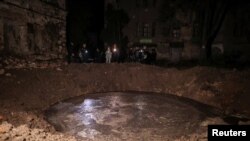 Поліцейські інспектують вирву, яка утворилася внаслідок ракетного удару біля медустанови. 27 квітня 2024 року