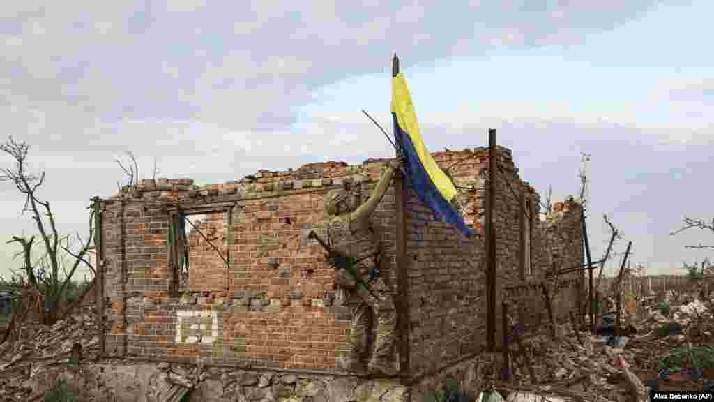A Ukrainian soldier places the national flag atop a destroyed home in the recaptured village of Andriyivka in the Donetsk region on September 16. The capture of both&nbsp;Andriyivka and&nbsp;Klishchiyivka -- which are situated on higher ground -- would allow&nbsp;Ukraine&rsquo;s troops to attack entrenched Russian forces in Bakhmut from the north and south.&nbsp;&nbsp; &nbsp;