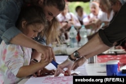Маці з дачкой размалёўваюць ручнік традыцыйнымі ўзорамі праз шаблён, фэстываль «Сонцаграй», чэрвень 2023