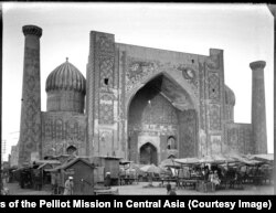 Площадь Регистан, исторический центр Самарканда. На площади расположились торговцы со своими лотками. Здание под сводом – медресе Шердор (медресе со львами).