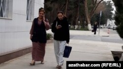 Mobile telefonda gürleşip we oňa seredip barýan zenanlar (Illýustrasiýa suraty)