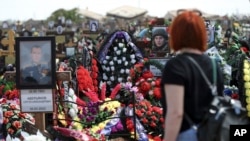 A woman looks at the graves of Russian soldiers at a cemetery in Volzhsky, outside Volgograd, Russia, in May 2022. A U.K. military official says Russia is nearing 700,000 killed or wounded since the full-scale invasion began.