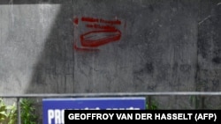 Graffiti depicting a coffin and the words "French soldiers in Ukraine" is seen behind a fence reading "Private Property" in Paris.