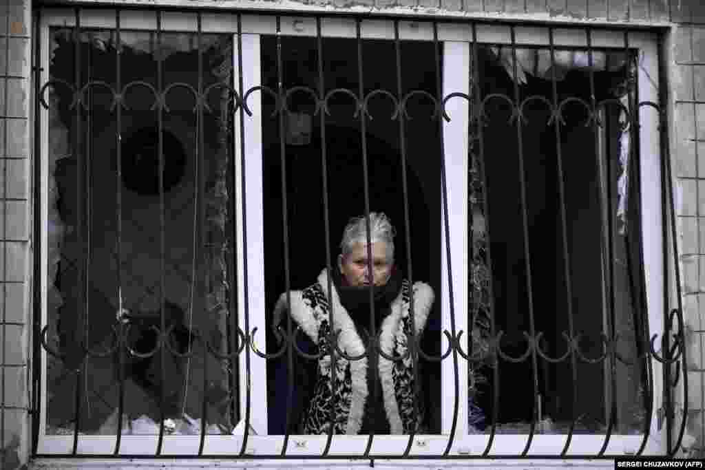 A woman surveys the scene from her apartment whose windows were blown out during the attack. Both Moscow and Kyiv deny targeting civilians in the nearly 22-month-long war that Russia launched against its neighbor in February 2022.