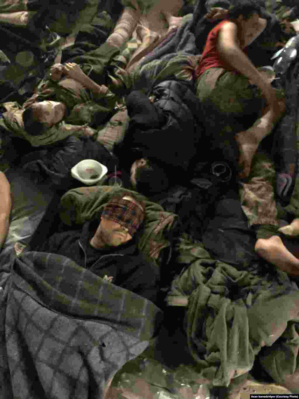 Azovstalniñ bomba sığınalarından birinde arbiy gospital. Asannıñ aytqanına köre, bazıda mında yaralanğanlarnıñ sayısı beş yüz insanğa yetken edi: &quot;Qan, kesilgen ayaq-qol, irin, necaset, sidik, teri... ve büyük dımlıq. Çünki eñ az 300 insan aynı vaqıtta bir odada, büyük bir mağazda nefes ala&quot;