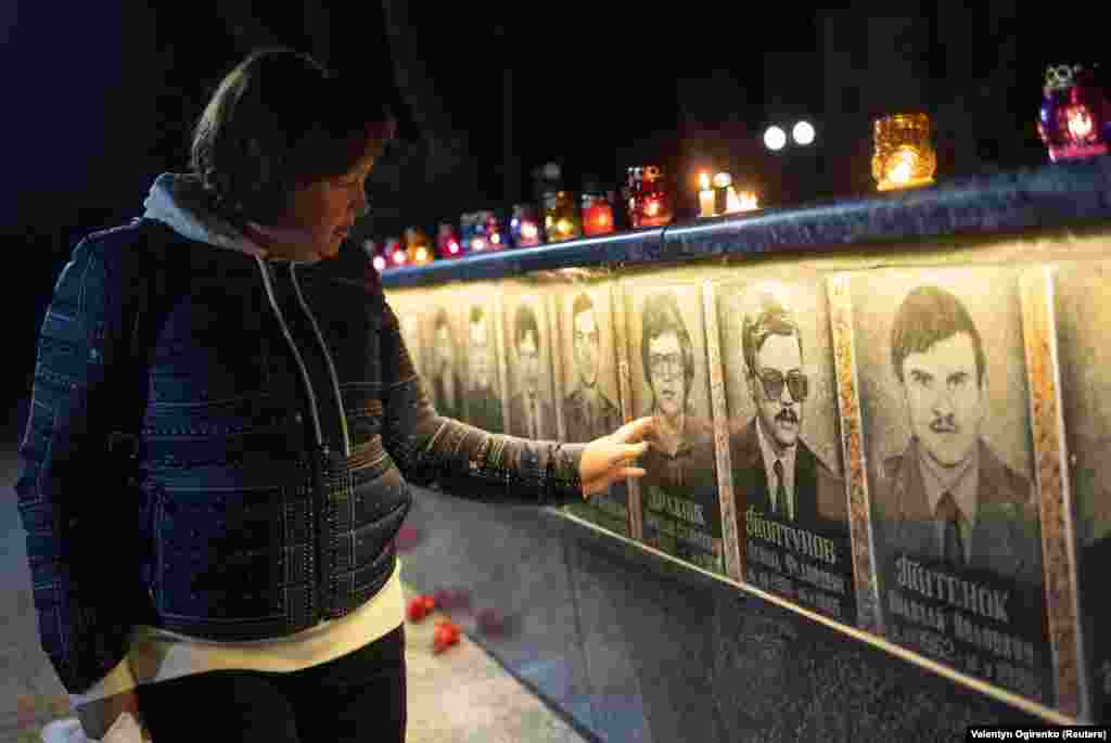 Жінка торкається фото на меморіалі пожежникам та працівникам ЧАЕС, жертвам аварії 1986 року, Славутич, 26 квітня 2023 року &nbsp;