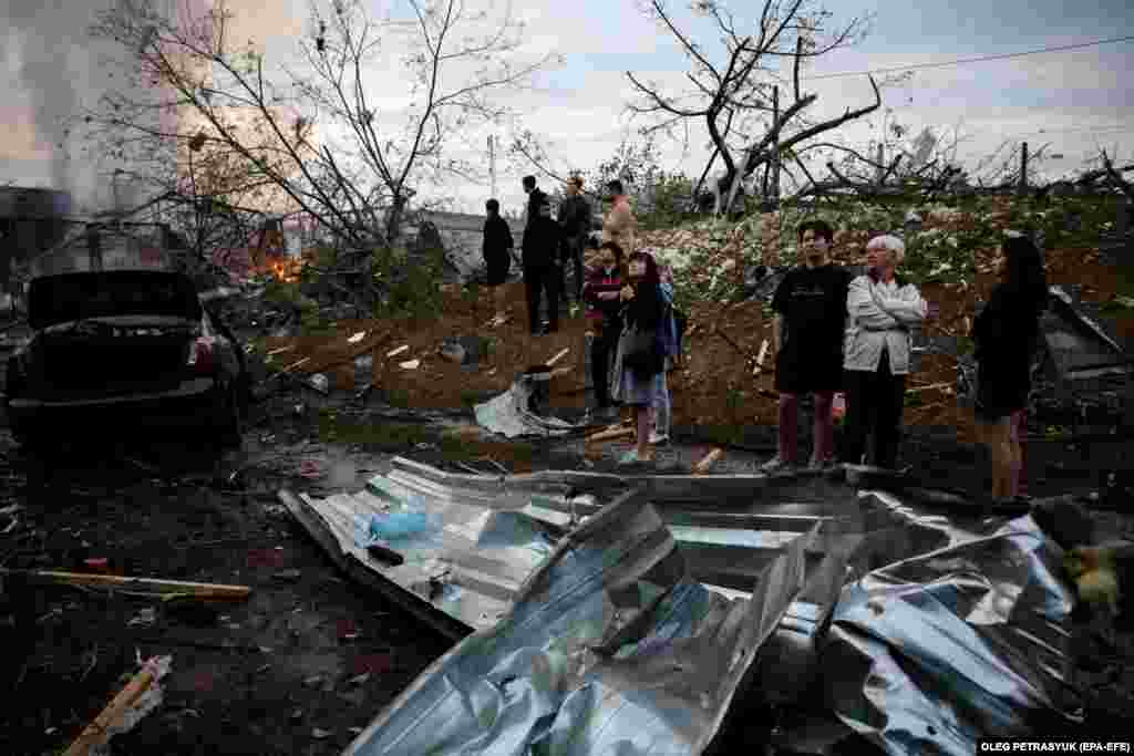 Люди стоять біля місця ракетного обстрілу в одному з житлових районів столиці, позаду палає пожежа, Київ, 21 вересня 2021 року. Українські військові знищили 36 з 43 ракет, якими вранці російські війська атакували Україну, повідомили Повітряні сили ЗСУ