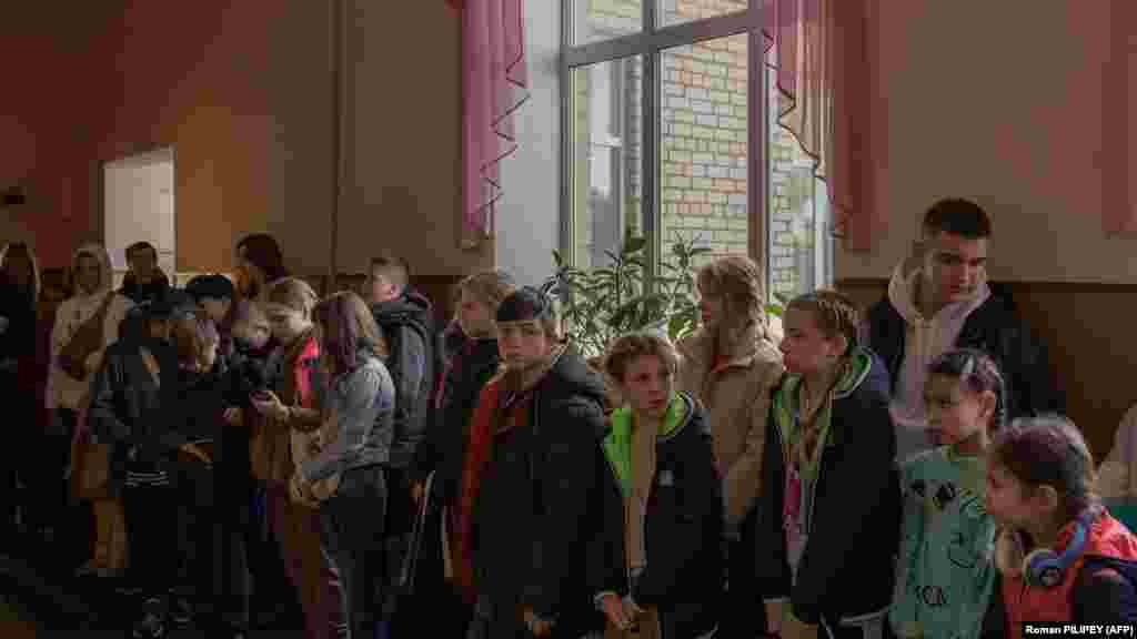 Діти збираються перед евакуацією, Херсон, 30 жовтня 2023 року. Надія Кондраткова, мати двох доньок, яка вперше розлучається зі своїми дітьми, тремтіла від страху, а її очі наповнилися слізьми. &laquo;Їм потрібно відпочити подалі від вибухів і сирен&raquo;, &ndash; пояснила Кондраткова своє рішення відправити своїх доньок з Херсону. &laquo;Вони виснажені &ndash; каже вона. &ndash;&nbsp;Вони вже не можуть спати і кричать ночами&raquo;