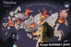 Український військовий проходить повз банер у центрі столиці України із зображенням мапи Росії у вогні та написом англійською: «Імперія зла має впасти». Київ, 26 жовтня 2023 року. Світлина агентства AFP