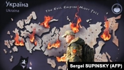 Український військовий проходить повз банер у центрі столиці України із зображенням мапи Росії у вогні та написом англійською: «Імперія зла має впасти». Київ, 26 жовтня 2023 року. Світлина агентства AFP