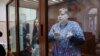 Aleksandra Bayazitova and Olga Arkharova stand in a defendants' cage while attending a court hearing in Moscow. 