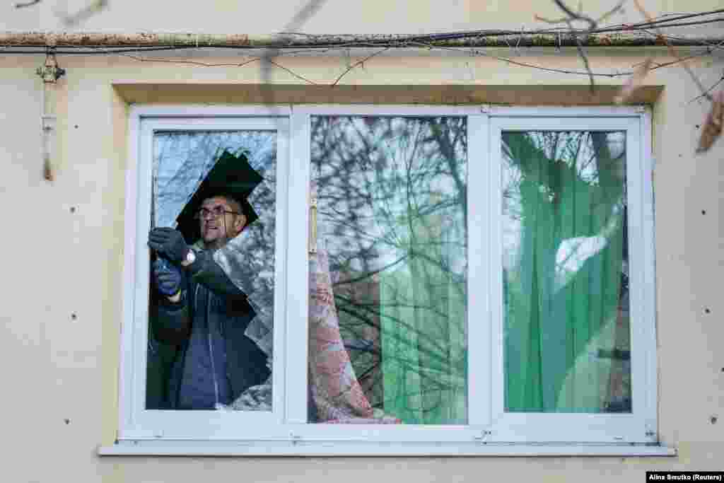Місцевий житель виймає бите скло з вікна своєї квартири, яке було пошкоджене під час атаки. Попри докази і свідчення, Москва від початку&nbsp;повномасштабного вторгнення&nbsp;заперечує цілеспрямовану&nbsp;атаку на цивільних.