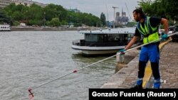 Муніципальний службовець демонструє відбір проб води річки Сени біля собору Паризької Богоматері під час прес-презентації перед Олімпійськими та Паралімпійськими іграми в Парижі, Франція, 15 липня 2024 року