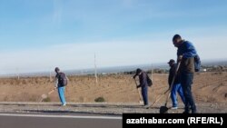 Işçiler Aşgabadyň daşyndaky gara ýoly bejerýär. (arhiw suraty) 
