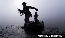 Український військовослужбовець вистрибує з човна біля берега Дніпра на Херсонщині, 15 жовтня 2023 року