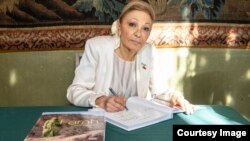 شهبانو فرح پهلوی در حال امضای نسخه‌ای از کتاب «فرح»