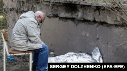 Орусия армиясынын соккусунан өмүрү кыйылган тогуз жашар секелектин сөөгүнүн жанында отурган атасы. 1-июнь, 2023-жыл. Киев. 