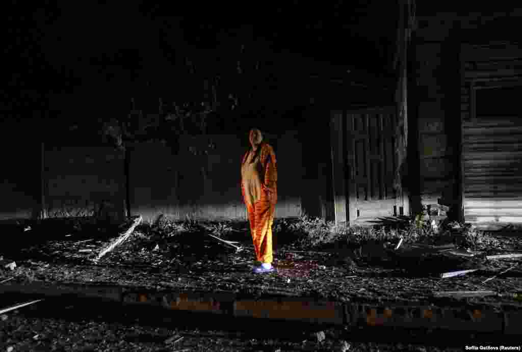 A local resident dressed in pajamas watches emergency personnel at work. &nbsp;