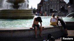 Люди намагаються охолодитися біля фонтану на Трафальгарській площі, Лондон, під час чергової теплової хвилі, липень 2022 року