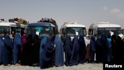 Displaced Afghan women wait to receive cash aid for displaced people in Kabul.