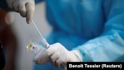 Мэдык у ахоўным камбінэзоне з наборам для тэставаньня на каранавірус