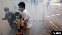 Полициянын чабуулунан качып, тилектешин куткарып бараткан демонстранттар. Гонконг. 24-май, 2020-жыл. 