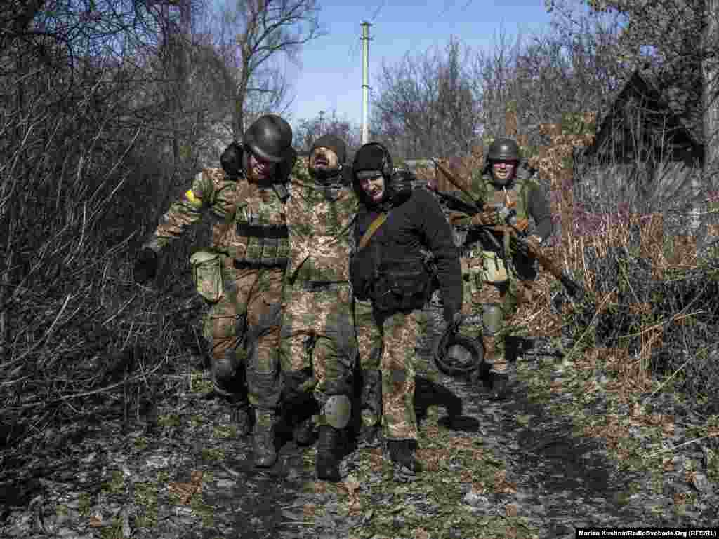 Військові ЗСУ несуть пораненого побратима після штурму населеного пункту, де перебували російські військові. Київщина, 10 березня 2022 року