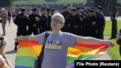 A participant poses with a rainbow flag with Interior Ministry officers in the background during an LGBT rally in St. Petersburg in 2017.