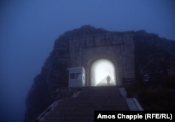 Охранител излиза от обвития в мъгла тунел с 461 стъпала, който води от паркинга до мавзолея на върха на планината Ловчен.