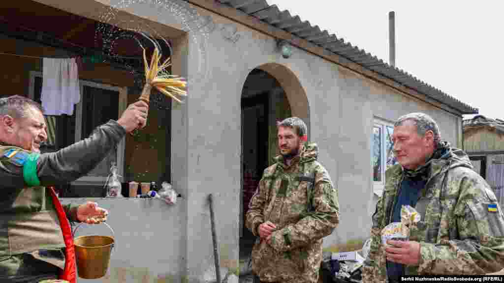 Військовий капелан Максим окроплює свяченою водою українських військових під час Великоднього богослужіння на їхніх позиціях. Харківська область, 24 квітня 2022 року