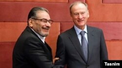 Iran's Ali Shamkhani (left) and Russia's Nikolai Patrushev shake hands in Tehran on November 9.