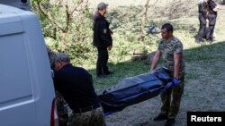 Forensic specialists load the body of a girl killed during a Russian missile strike in a van in Kyiv on June 1.