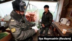 A Russian police officer checks the documents of a Kyrgyz migrant worker. (file photo)