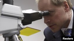 Денсаулық саласы шенеунігі микроскопқа қарап тұр.  (Көрнекі сурет)