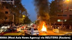 A police motorcycle burns as protesters take to the streets in Tehran. 