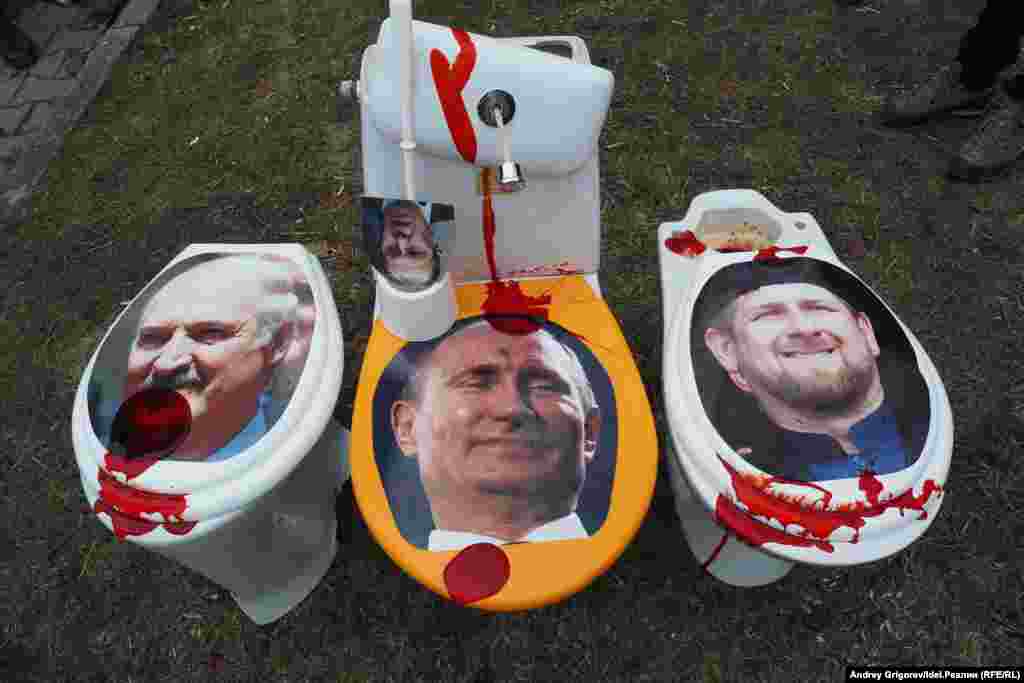 Лица лидера Беларуси Александра Лукашенко (слева), президента России Владимира Путина (в центре) и главы Чечни Рамзана Кадырова на сиденьях унитазов, забрызганных красной краской, что символизирует пролитую кровь &nbsp;