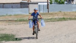 Мальчик везет воду на велосипеде. Село Кызылсуат. Акмолинская область, 10 июня 2020 года.