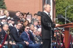 Сидевшие на трибуне были в подавляющем большинстве без масок (сообщалось, что ветераны, приглашенные смотреть парад, провели несколько дней в изоляции).