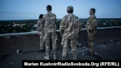 Медики-добровольці на даху дев’ятиповерхівки спостерігають за вечірнім боєм на території авдіївської промзони