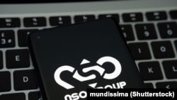 NSO Group logo seen on the smartphone placed on laptop keyboard. Israeli company known for its Pegasus spyware for surveillance.