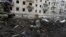 Police officers inspect a crater in front of a damaged residential building hit by a Russian strike in Kharkiv on March 27.