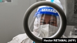 A health worker waits for people to take swab samples to test for the coronavirus in the Jing'an district in Shanghai on December 23.