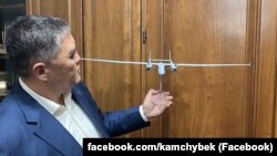 Камчыбек Ташиев держит в руках макет беспилотника «Аксунгур».