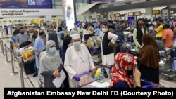 Afghan citizens wait for airline transfers at the airport in New Delhi, India, following the Taliban's takeover of Afghanistan last August.